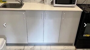 Een keuken met een spoelbak, een magnetron en kastjes.