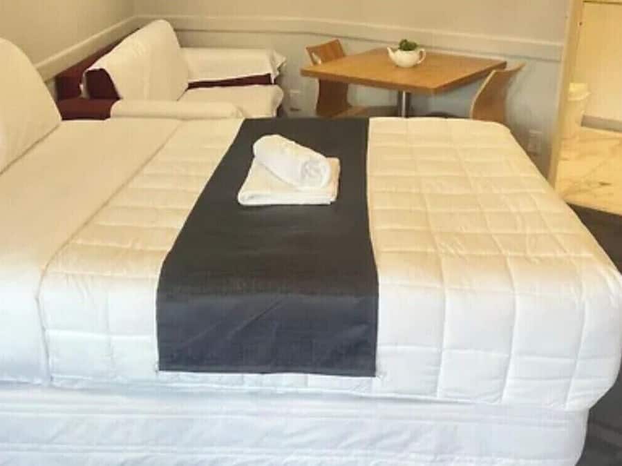 A hotel room with a large bed, a small table, and a chair.