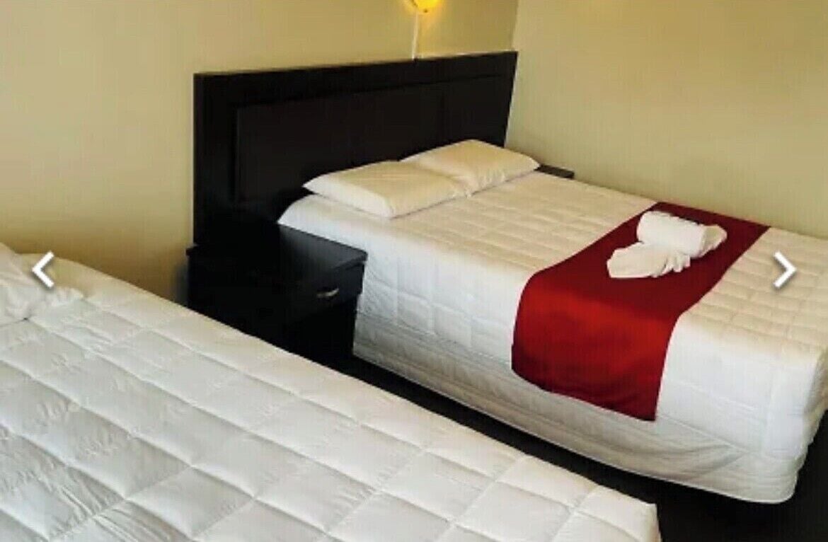Et hotelværelse med en enkelt seng, et natbord og en sengetablelampe.