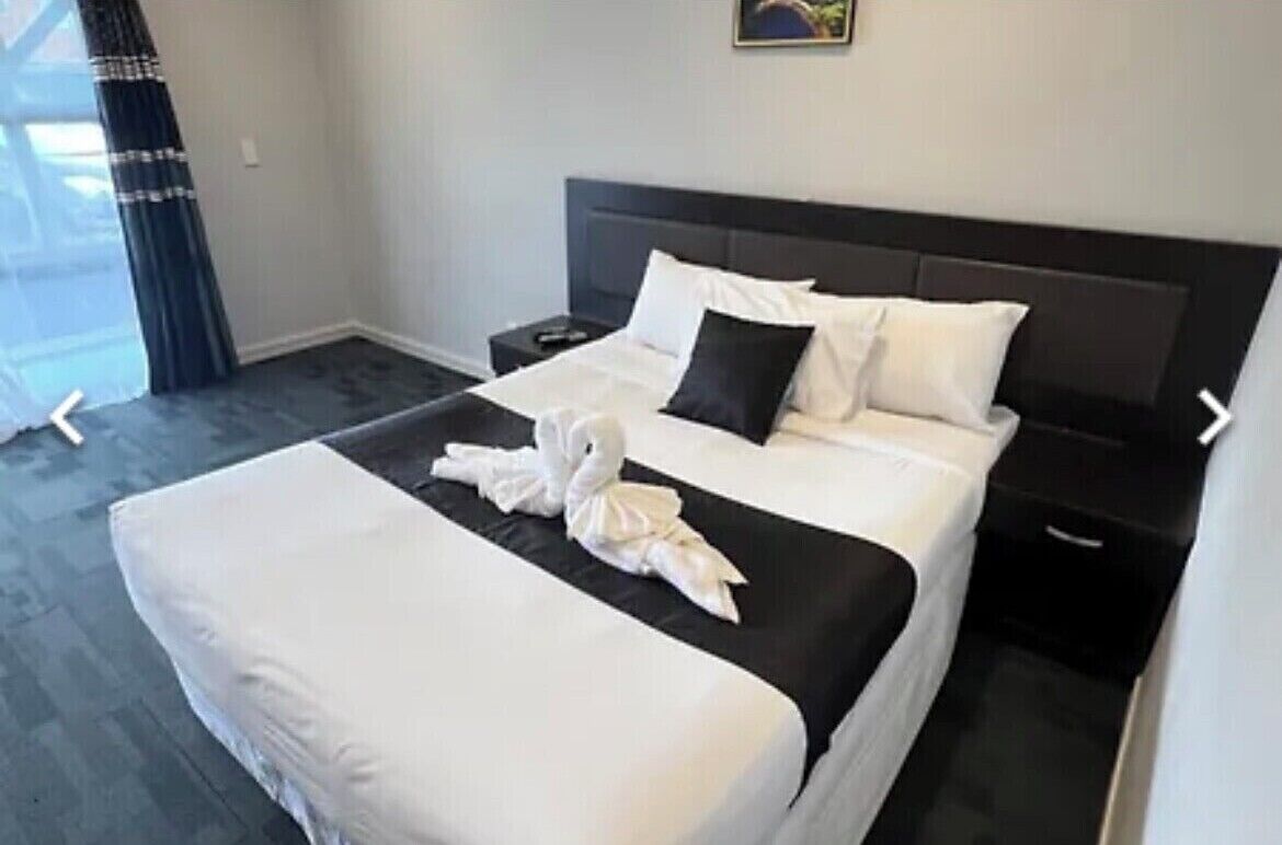 Une chambre d’hôtel avec un grand lit, une table de chevet et une fenêtre avec des rideaux.