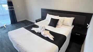 Une chambre d’hôtel avec un grand lit, une table de chevet et une fenêtre avec des rideaux.