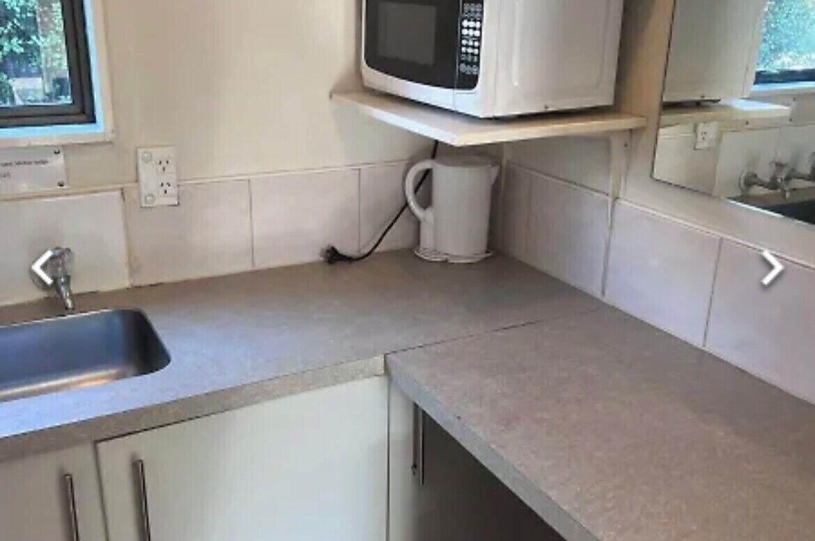 Een keuken met een ingebouwde magnetron, een koffiezetapparaat en een spoelbak.