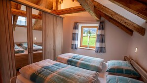 Ein Schlafzimmer mit zwei Betten, einem Holzschrank und einem Fenster mit Vorhängen.