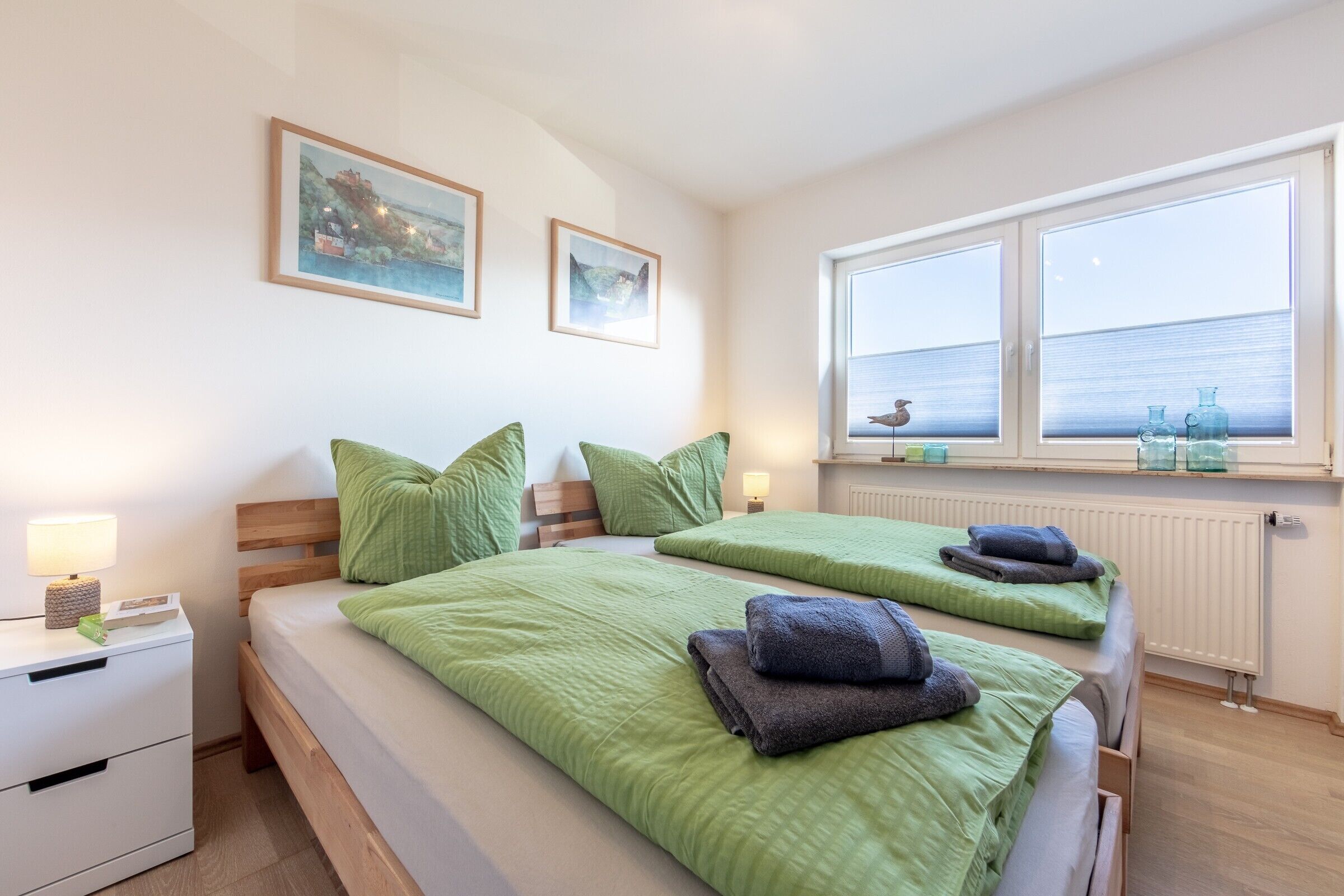Un lit double avec une literie verte, une table de chevet avec une lampe et une fenêtre donnant sur la mer.