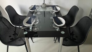 A dining table with four chairs, each with a dark napkin and a glass.