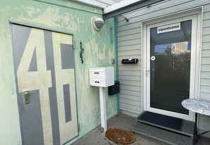 Une porte avec un grand numéro « 4 », une boîte aux lettres, un interphone et une pancarte de bienvenue.