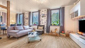 Un salon avec un canapé, une table basse en verre, un téléviseur et une cheminée.