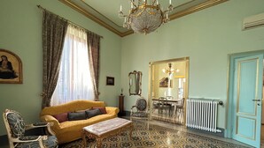 Une pièce avec un sol à motifs, un canapé jaune, une table basse en bois et un lustre.