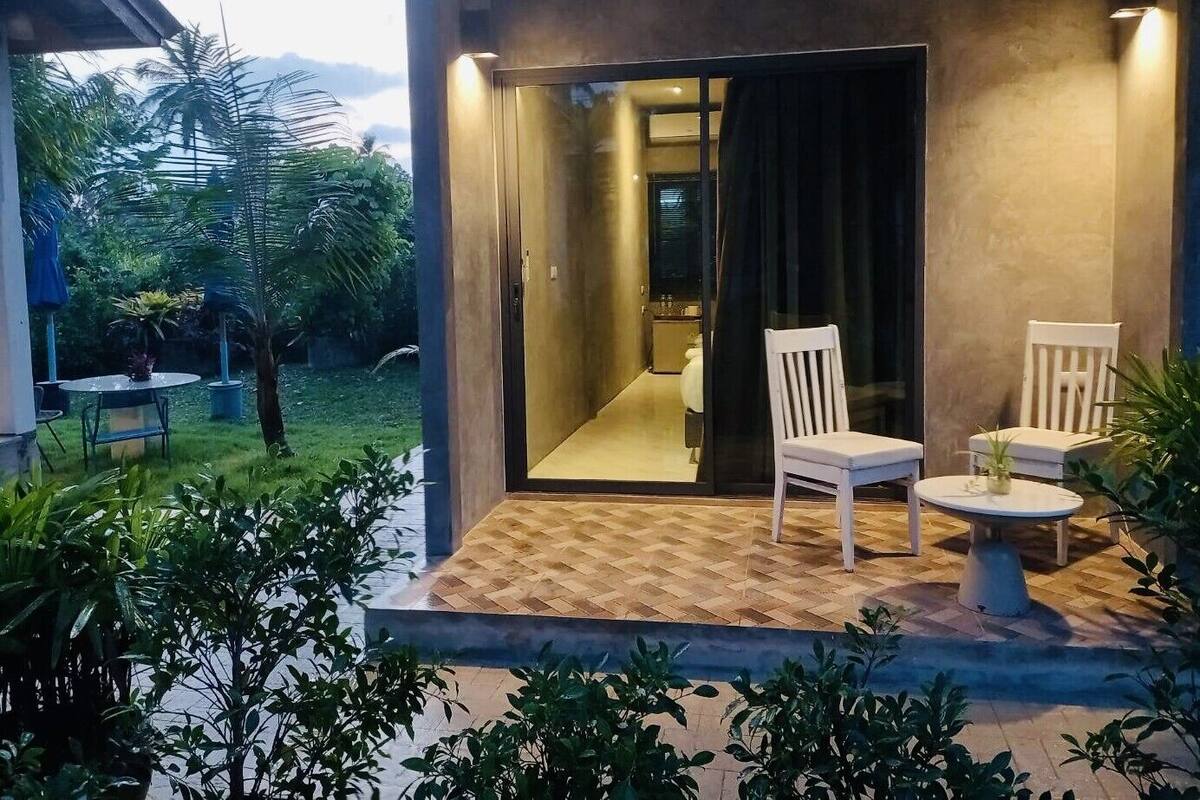 A modern outdoor area with a wooden deck, two white chairs, and a small table.