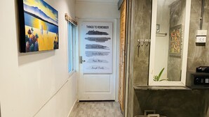 Un pasillo con una puerta que muestra 'THINGS TO REMEMBER' con frases motivacionales. Hay un cuadro en la pared y una cesta en el suelo.