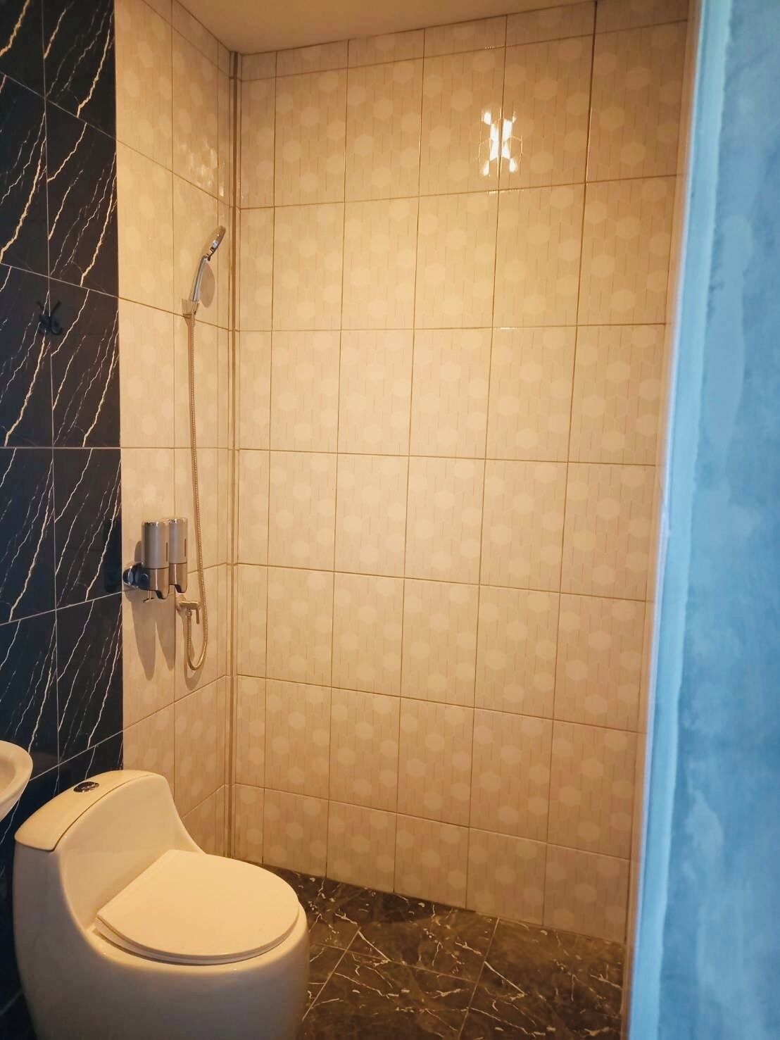 A bathroom with a toilet, a shower, and a marble floor.