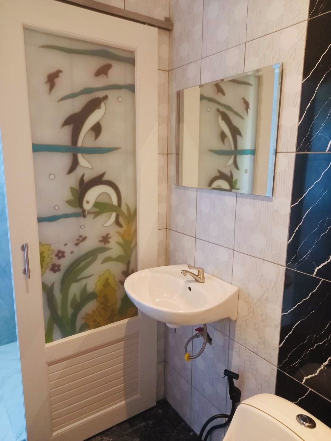 A bathroom with a glass shower door, a white sink, and a mirror above it.