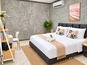 Une chambre moderne avec un grand lit, un mur gris à texture et un tableau sur le thème de la plage.