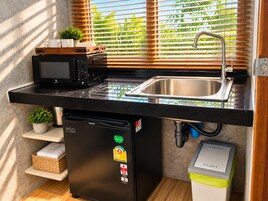 Una cocina compacta con microondas integrado, un lavamanos de acero inoxidable y lavavajillas.