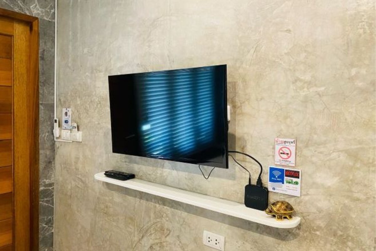 Un televisor de pantalla plana montado en la pared, con un estante debajo.