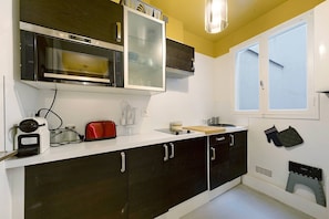 A kitchen with a microwave, toaster, and a window with a view.