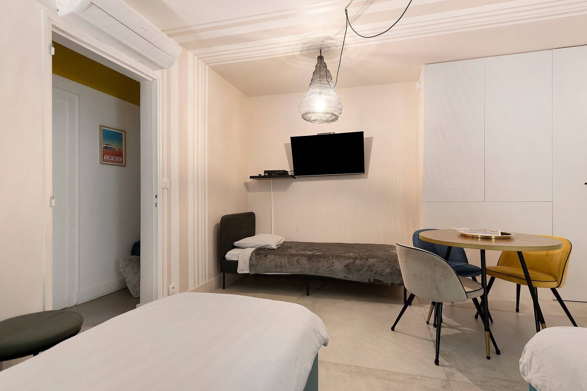 A bedroom with a bed, a desk, a chair, a television, and a dining table.