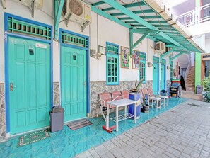 A building with turquoise doors and a covered outdoor seating area. - Hotel O Hotel New Tirken (Tegal)