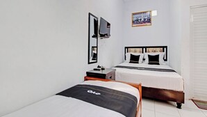 Habitación de hotel con dos camas individuales, una mesita de noche pequeña, un espejo y un cuadro en la pared.