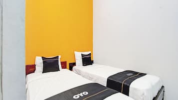 Quarto de hotel com duas camas, cada uma com roupa de cama branca e cabeceiras pretas.