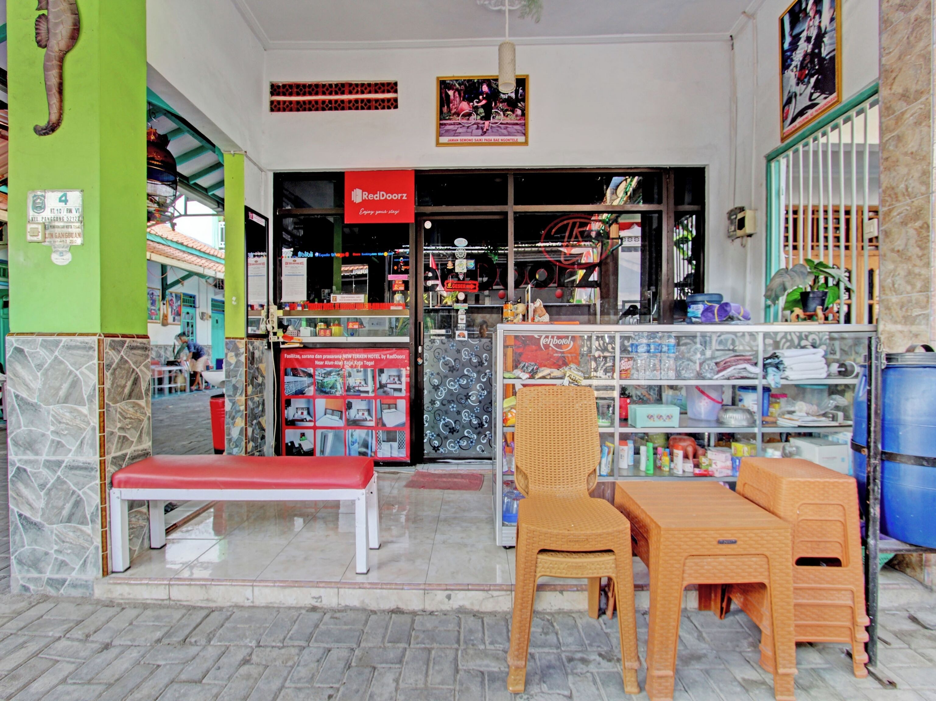 A RedDoorz store with a RedDoorz sign, a bench, and a wicker chair outside.