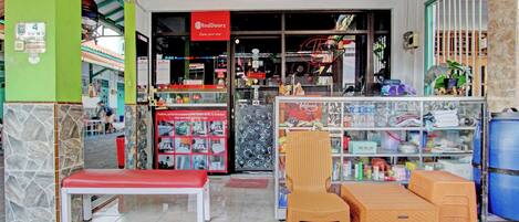 A RedDoorz store with a RedDoorz sign, a bench, and a wicker chair outside.