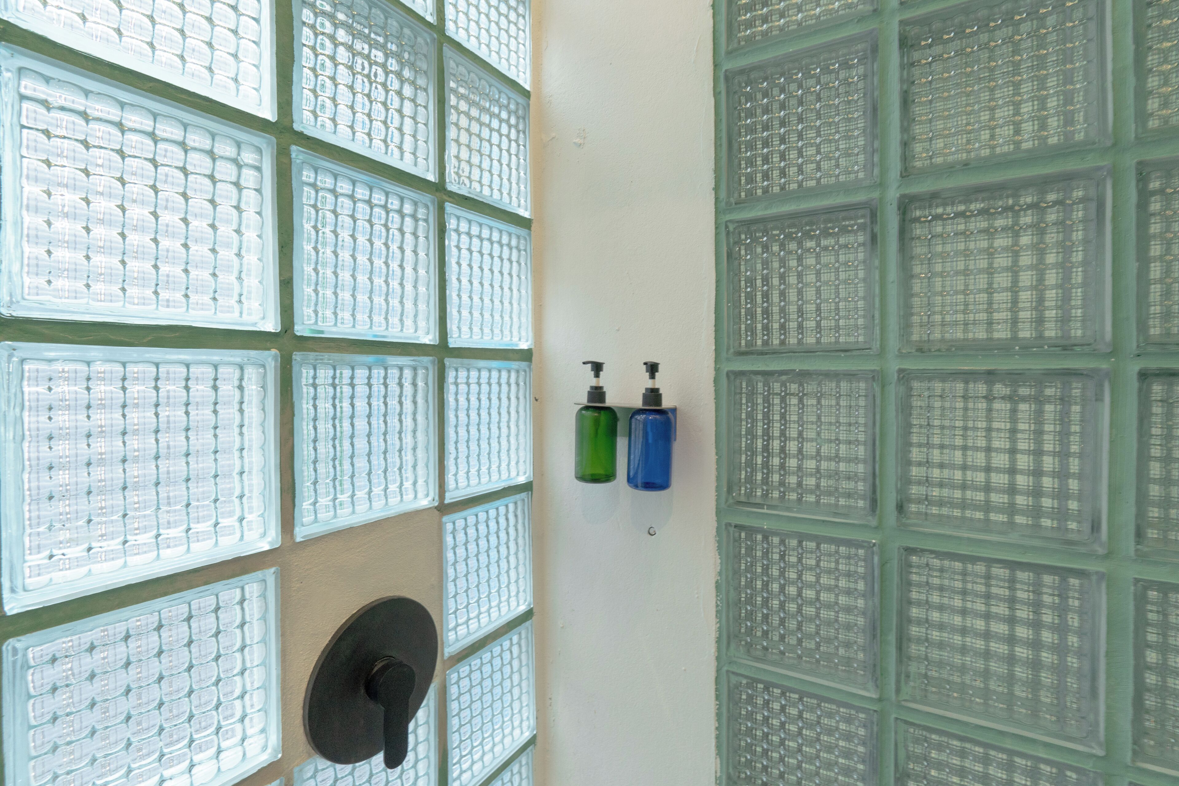 A bathroom with multiple windows, a sink, and two soap dispensers.