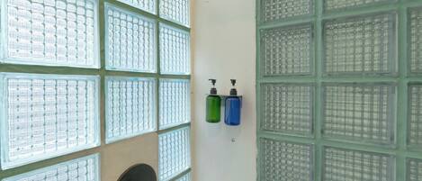 A bathroom with multiple windows, a sink, and two soap dispensers.