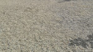 Une maison moderne avec un mur en pierre, une terrasse en bois et une allée gravillonnée.