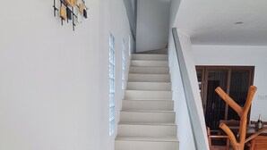 Un escalier au design moderne mène à un espace repas agrémenté d’une table et de chaises en bois.