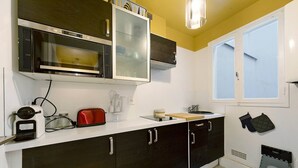Eine Küche mit Mikrowelle, Toaster und Backofen, ein Fenster mit Aussicht und ein Spülbecken.