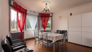A dining area with a table, chairs, a chandelier, and a view through the windows. - Holiday Home 'Maison Dans Le Morbihan' with Private Garden (Val d'Oust)