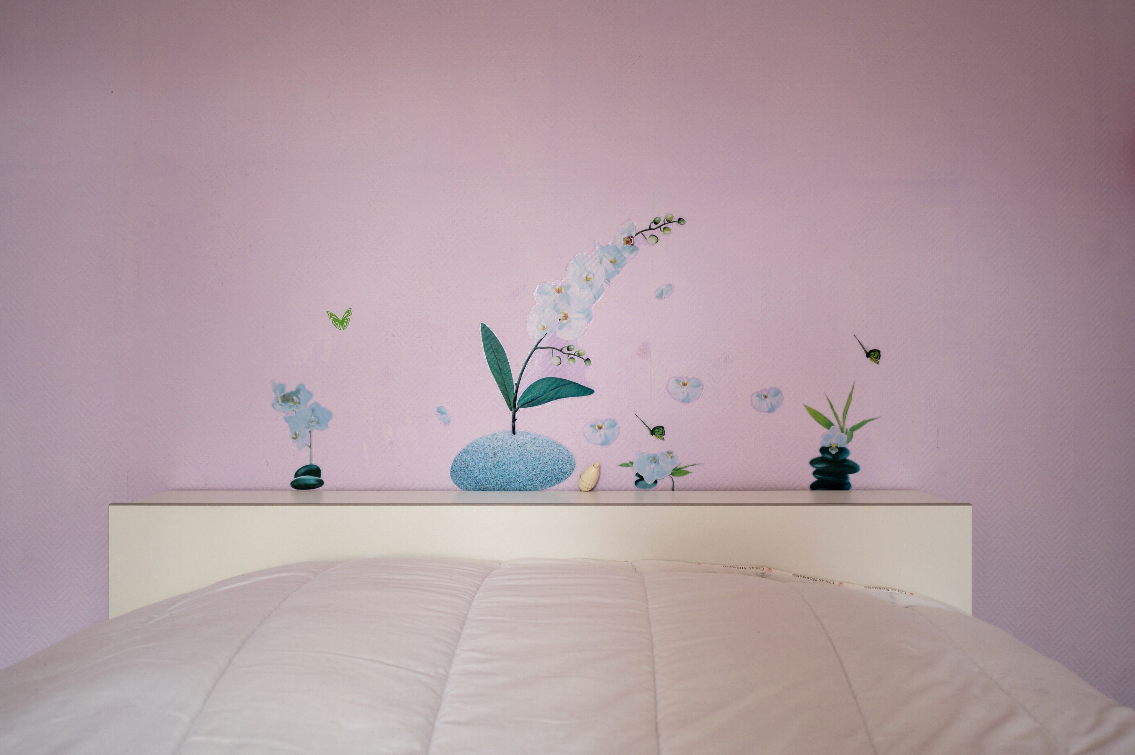 Un dormitorio con cama, mesita de noche y estantes en la pared decorados con objetos.