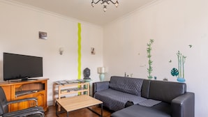 A living room with a sofa, a TV, a wooden coffee table, and a lamp. - Holiday Home 'Maison Dans Le Morbihan' with Private Garden (Val d'Oust)