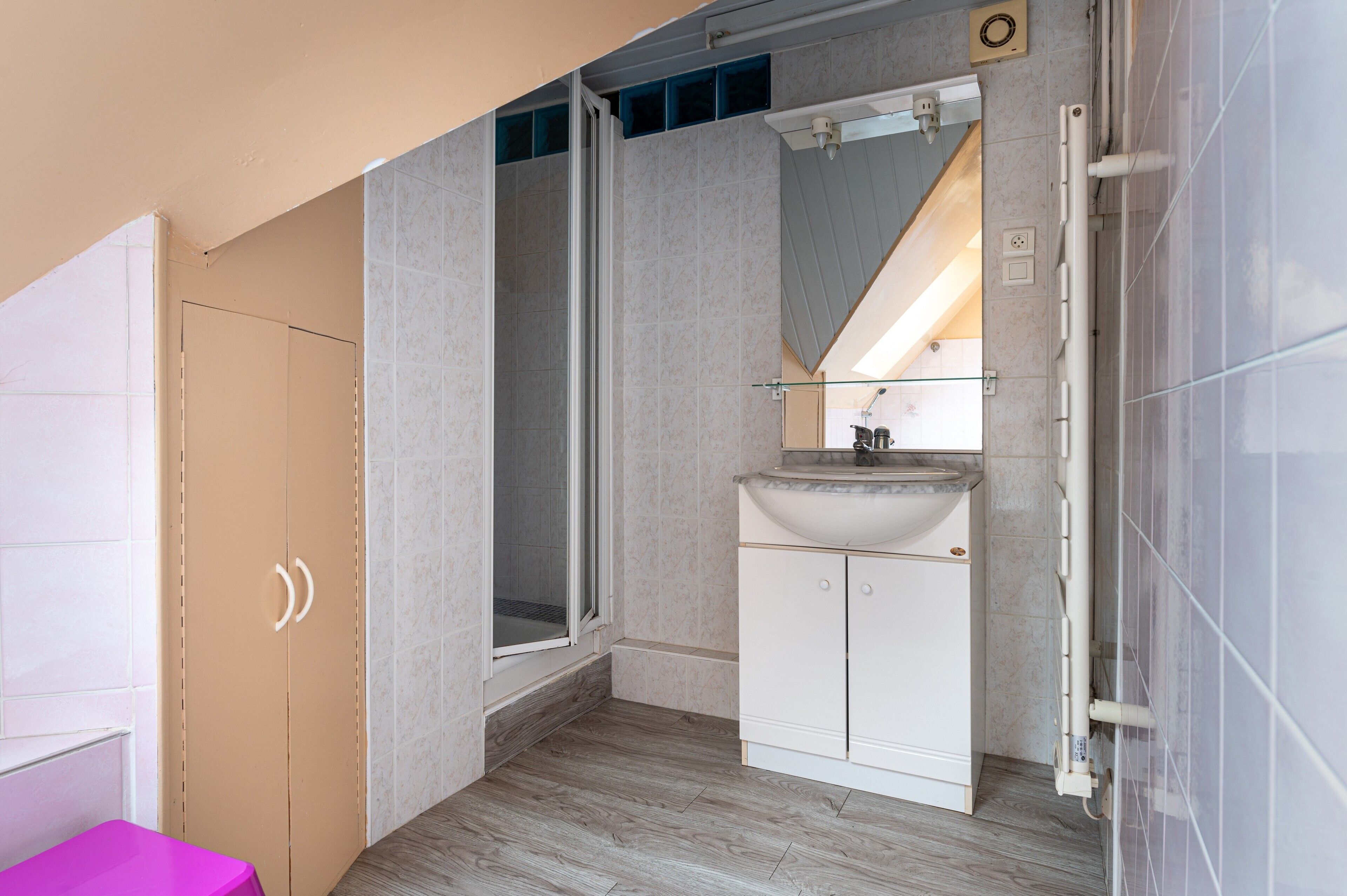 Een badkamer met een douche, wastafel en kast.