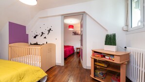 A child's room with a crib, a bed, a bookshelf, and a window. - Holiday Home 'Maison Dans Le Morbihan' with Private Garden (Val d'Oust)
