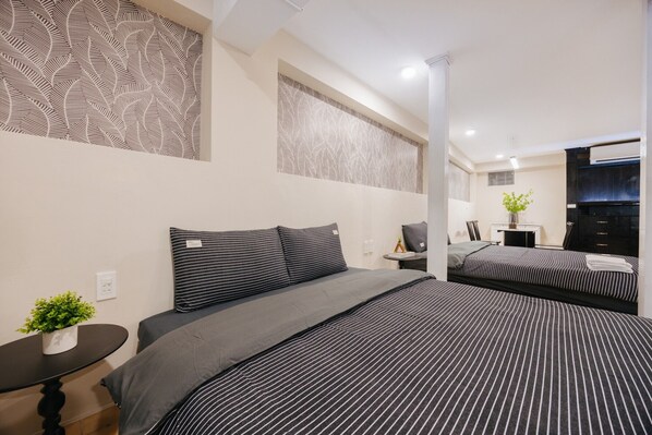 Una habitación de hotel moderna con una cama grande, una mesita con una planta y un televisor.