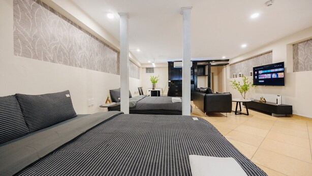 Una habitación de hotel moderna con una cama grande, un escritorio, un sofá y un televisor montado en la pared.
