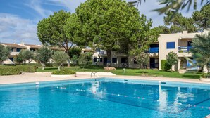 A swimming pool with clear blue water, surrounded by greenery and buildings with balconies. - Apartment 'The Triple House' with Shared Pool, Private Terrace and Wi-Fi (Alvor)
