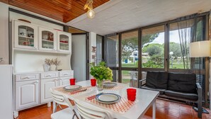 A dining area with a table set for two, white cabinets, a black sofa, and a view of the outdoors. - Apartment 'The Triple House' with Shared Pool, Private Terrace and Wi-Fi (Alvor)