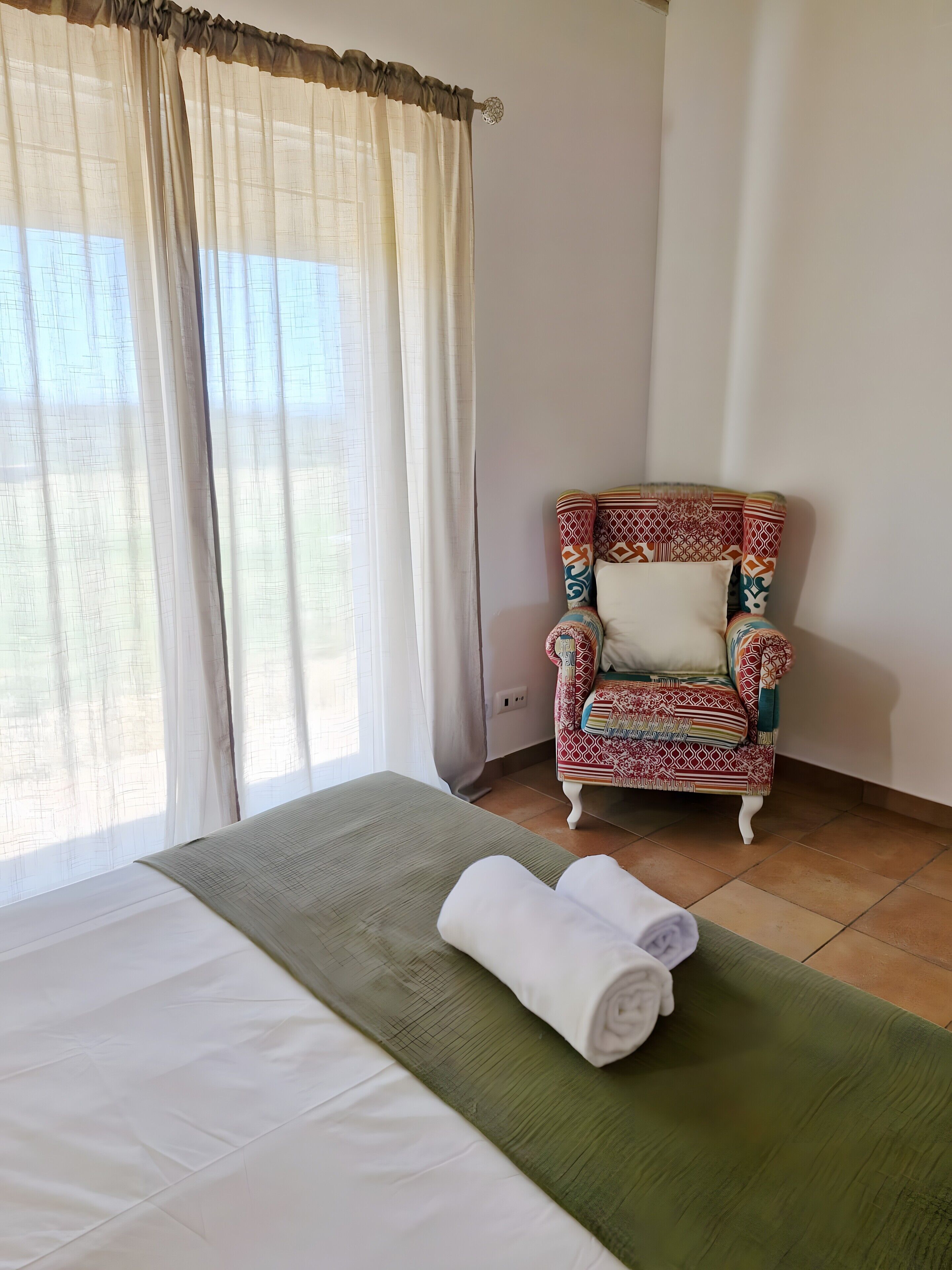 Ein Zimmer mit einem Bett, einem Stuhl und einem fensterbepflanzten Fenster.