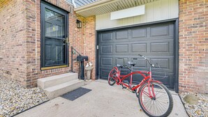 A red bicycle parked in front of a brick house with a black garage door. - 11 Mi to Dtwn Columbus: Group Retreat w/ Fire Pit! (Worthington)