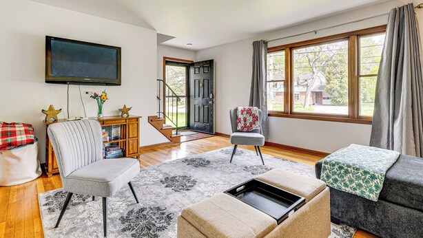 A modern living room with a flat-screen TV, a grey armchair, a sofa, and a coffee table. - 11 Mi to Dtwn Columbus: Group Retreat w/ Fire Pit! (Worthington)