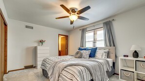 A bedroom with a bed, a ceiling fan, a nightstand, a lamp, and a window with curtains. - 11 Mi to Dtwn Columbus: Group Retreat w/ Fire Pit! (Worthington)