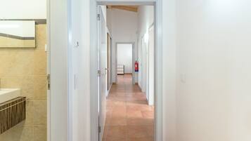 Un couloir doté d’un sol carrelé, de murs blancs et d’un extincteur fixé au mur.