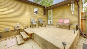 Une maison jaune dotée d’un patio, de meubles de jardin et d’une terrasse en bois.