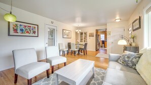 Un salon moderne comprenant un canapé, deux fauteuils, une table basse et un coin repas avec des chaises et une table.