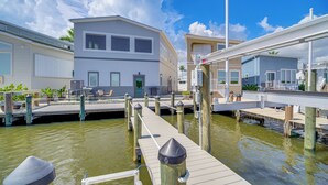Une propriété située au bord de l’eau, avec un quai menant à une maison dotée d’un balcon.
