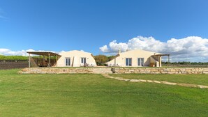 A two-story house with a stone foundation, a covered patio, and a grassy yard.