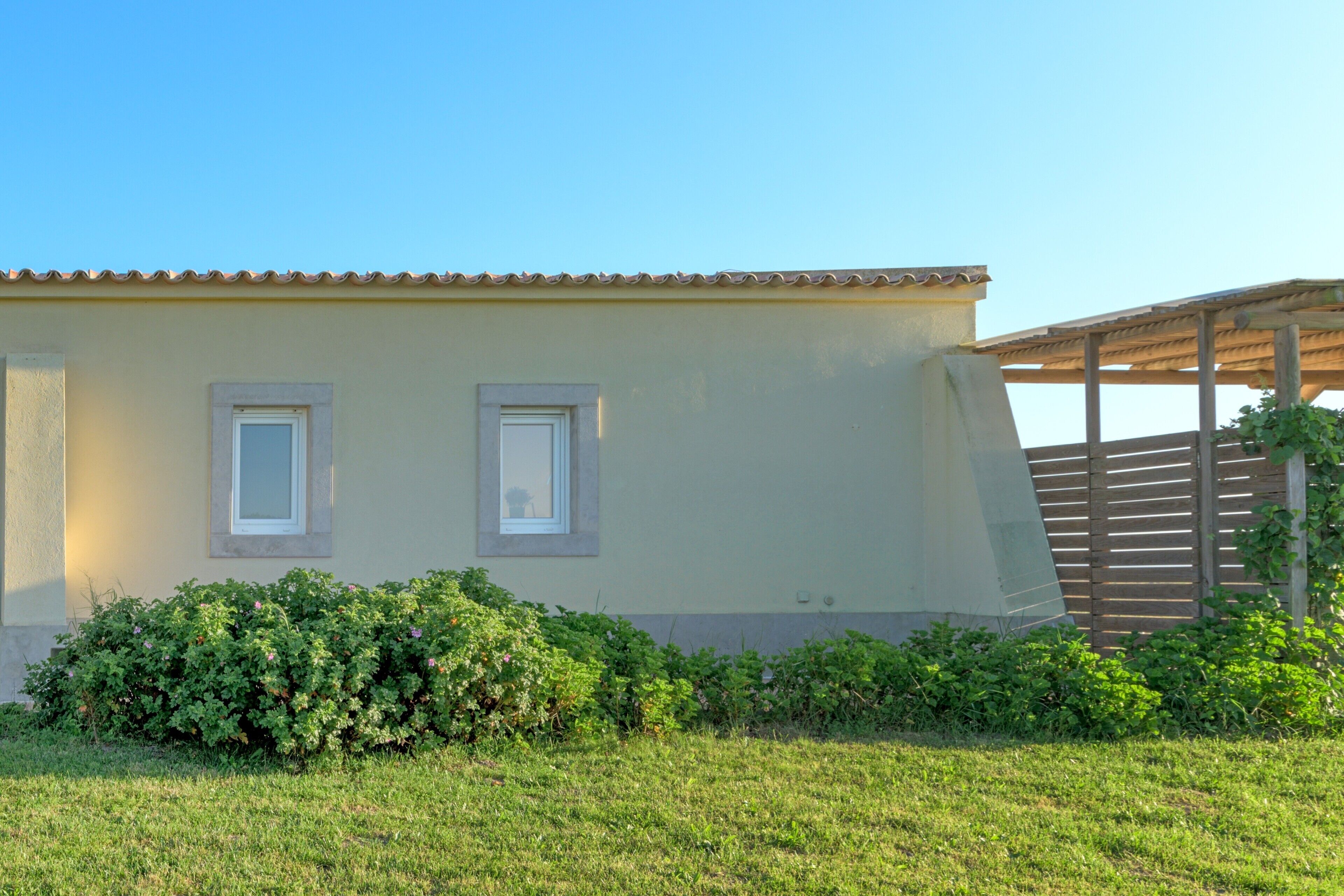 Un bâtiment doté d’un toit plat, de deux fenêtres et d’une clôture en bois.